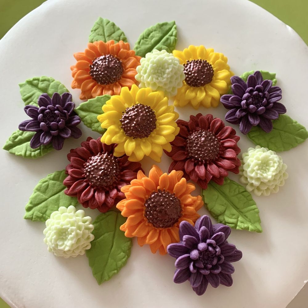 An 8-inch iced cake topped with sugar paste sunflowers, dahlias, chrysanthemums and green leaves