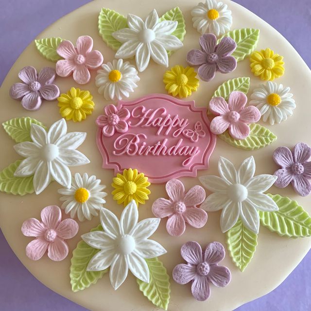Pastel sugar flowers around a Happy Birthday plaque